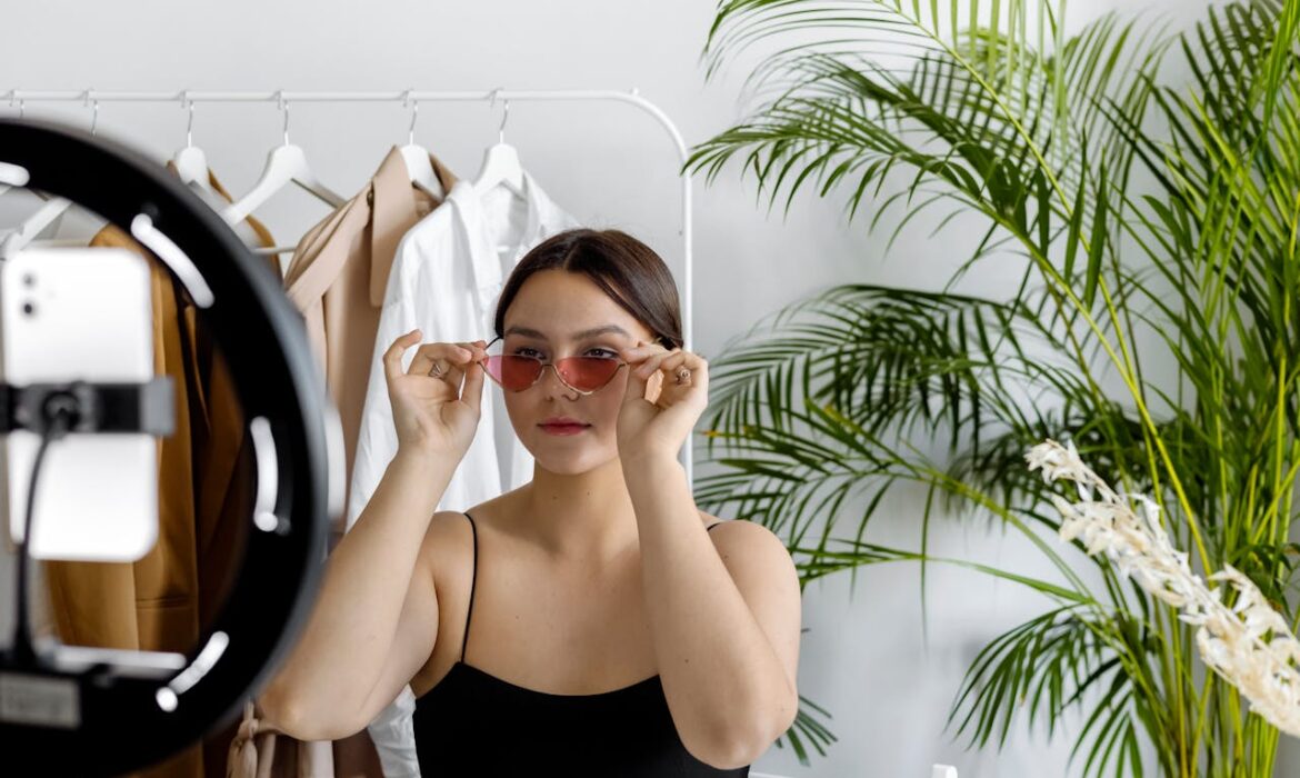 Fashion entrepreneur creating personal brand content with ring light and smartphone in minimalist studio