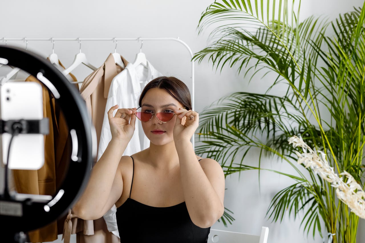 Fashion entrepreneur creating personal brand content with ring light and smartphone in minimalist studio