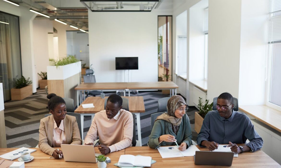 Professional business team collaborating on press release distribution strategy at modern office conference table with laptops and documents