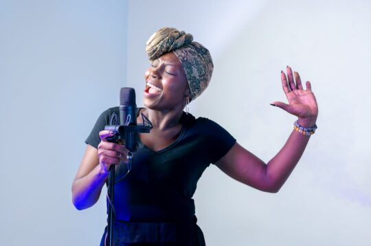 Woman singing passionately into microphone for Sheen Magazine feature