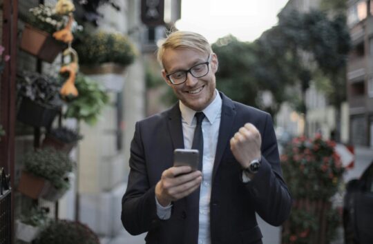 Entrepreneur celebrating success on phone after getting featured on Entrepreneur Magazine - Nextenco guaranteed placement service